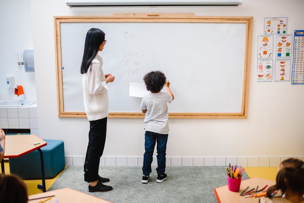 Woman And A Boy Standing By A Whiteboard In A Classroom 8466907 1024x683